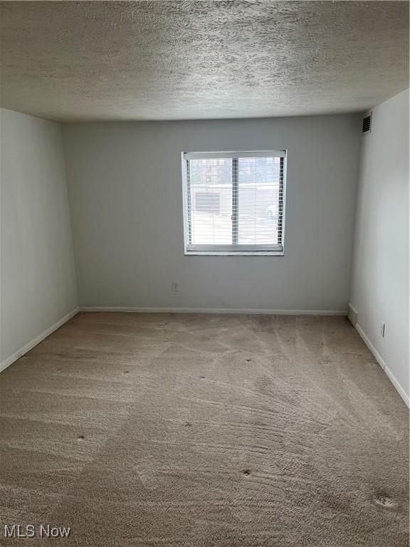 carpeted empty room with a textured ceiling