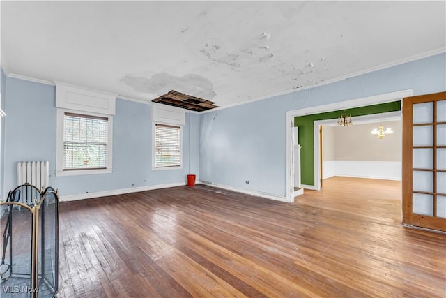 unfurnished room featuring crown molding, radiator heating unit, hardwood / wood-style floors, and a notable chandelier