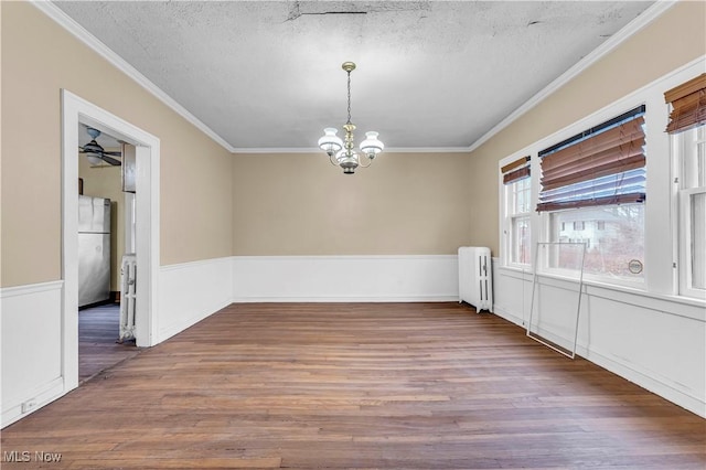 spare room featuring radiator heating unit, dark wood-type flooring, a textured ceiling, and ornamental molding