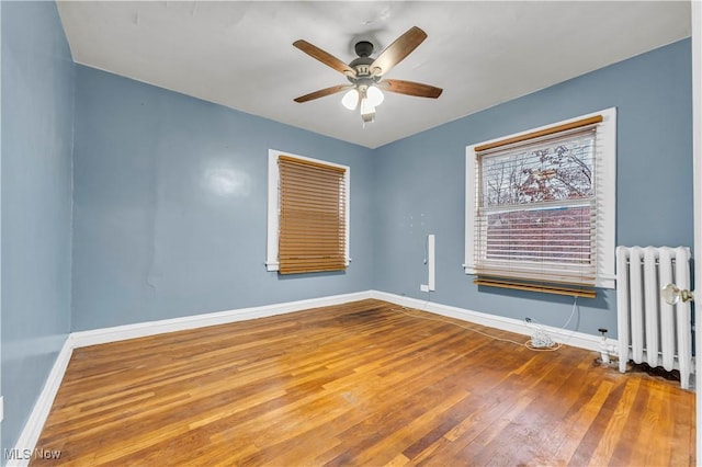 spare room featuring ceiling fan, radiator heating unit, and hardwood / wood-style flooring