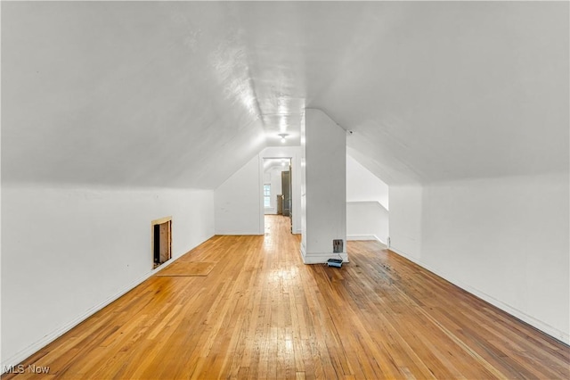 bonus room with light wood-type flooring and vaulted ceiling