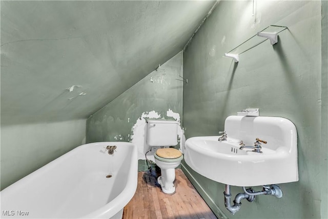 bathroom with hardwood / wood-style floors, sink, vaulted ceiling, a washtub, and toilet