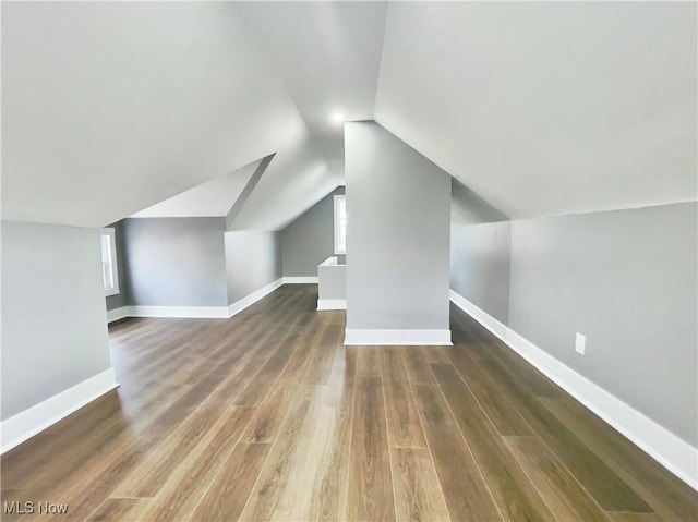 bonus room with dark wood-type flooring and vaulted ceiling