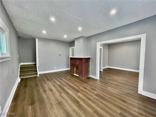 unfurnished living room with wood-type flooring and a textured ceiling