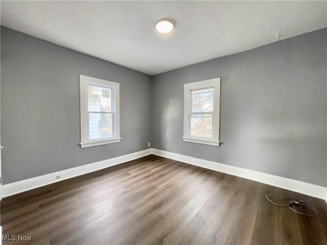 empty room with plenty of natural light and dark wood-type flooring