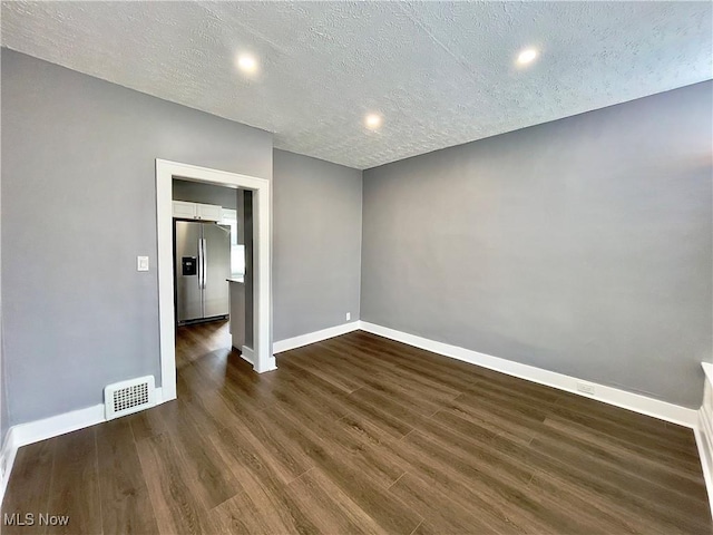 spare room featuring dark hardwood / wood-style floors and a textured ceiling