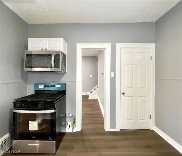 kitchen with stainless steel appliances, white cabinetry, and dark wood-type flooring