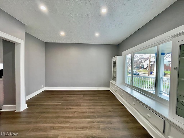 spare room featuring dark hardwood / wood-style flooring and a textured ceiling