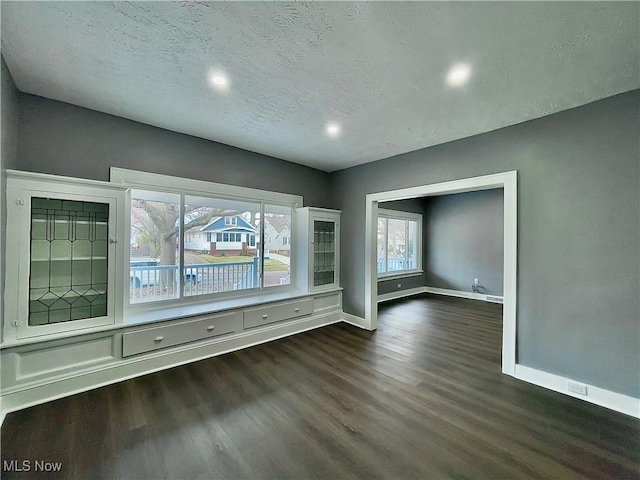 spare room featuring dark hardwood / wood-style flooring and a textured ceiling