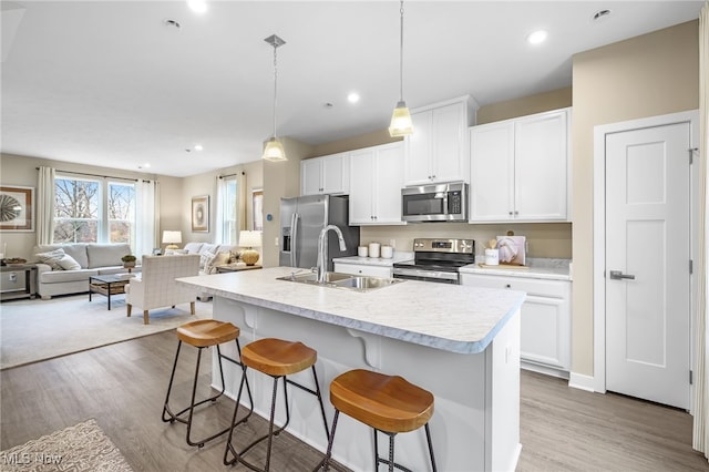 kitchen with pendant lighting, a center island with sink, a kitchen breakfast bar, sink, and stainless steel appliances