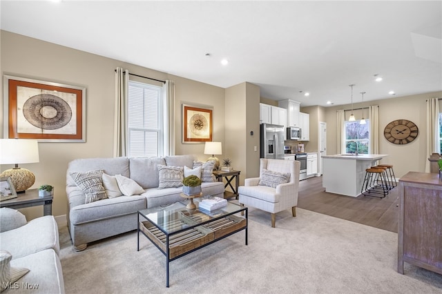 living room with a wealth of natural light, sink, and light wood-type flooring