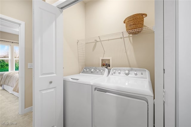 laundry room with independent washer and dryer and light colored carpet