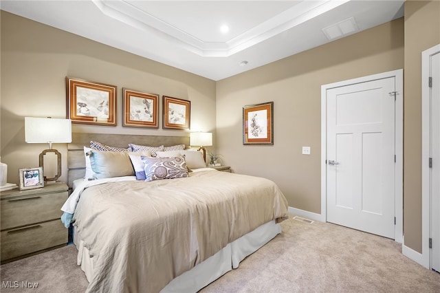 bedroom featuring light carpet and a tray ceiling