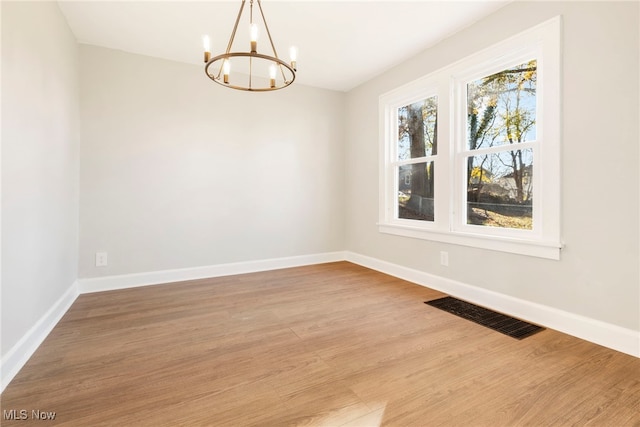 spare room featuring a notable chandelier and hardwood / wood-style floors