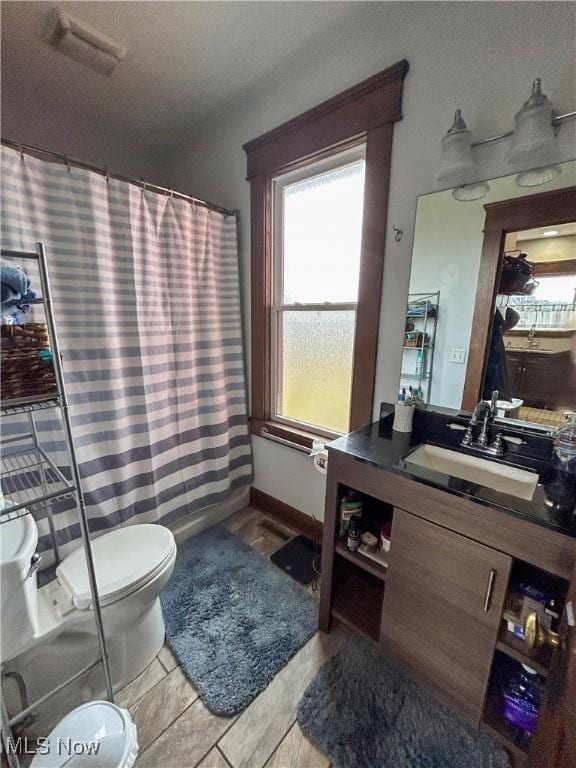 bathroom featuring curtained shower, vanity, and toilet