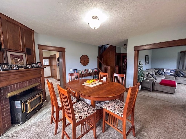 carpeted dining area featuring a wood stove and a textured ceiling