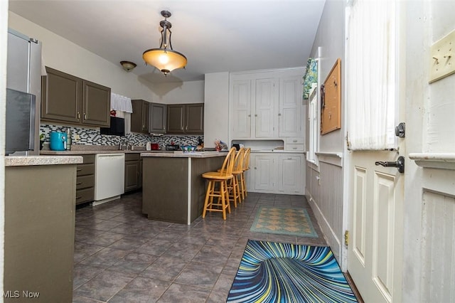 kitchen featuring dishwasher, a center island, decorative backsplash, and a breakfast bar