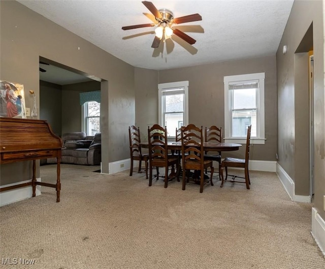 dining area featuring ceiling fan, light colored carpet, and a textured ceiling