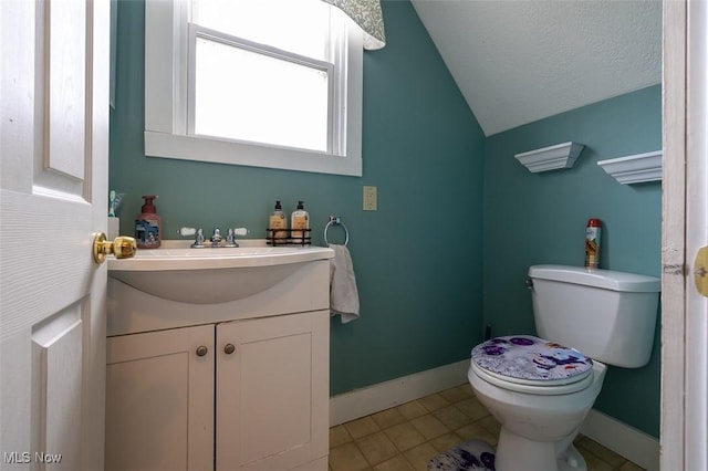 bathroom featuring tile patterned floors, a textured ceiling, vaulted ceiling, toilet, and vanity