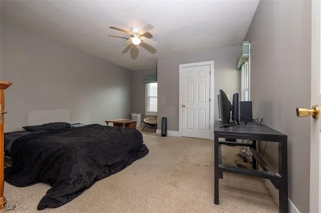 bedroom featuring a textured ceiling, light colored carpet, and ceiling fan