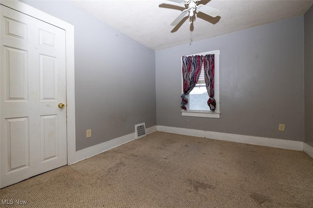 carpeted empty room featuring ceiling fan and a textured ceiling