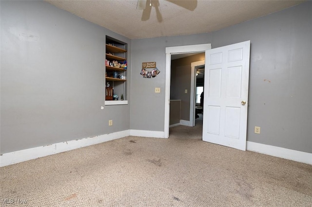 spare room featuring carpet flooring, ceiling fan, and a textured ceiling