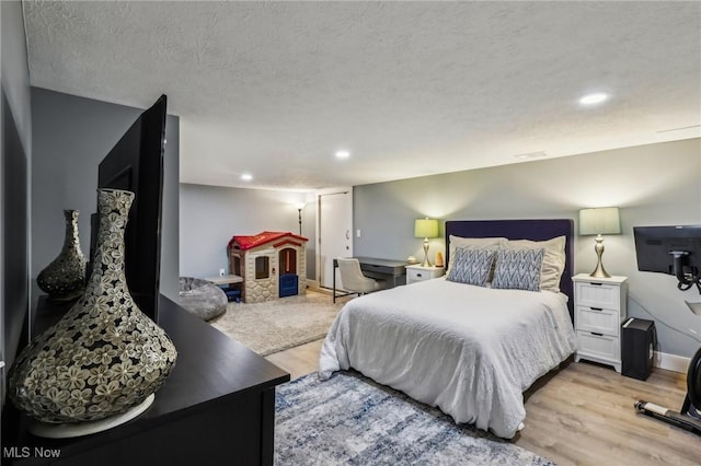 bedroom featuring light hardwood / wood-style flooring and a textured ceiling