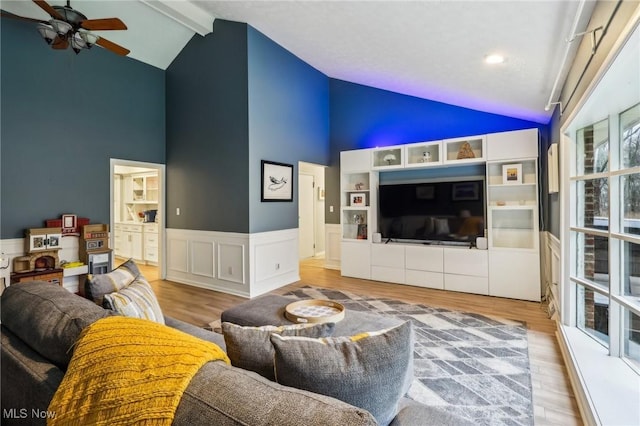 living room featuring ceiling fan, light hardwood / wood-style flooring, and lofted ceiling with beams