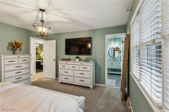 carpeted bedroom featuring ensuite bath and an inviting chandelier