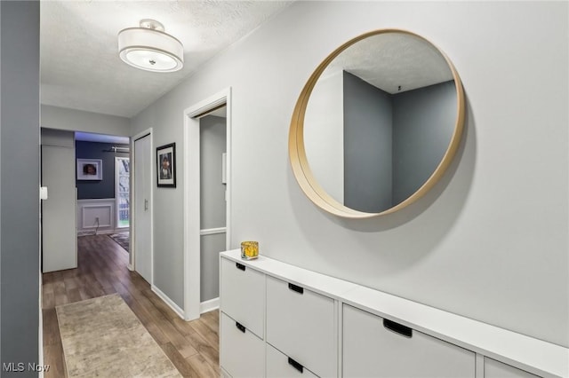 hall featuring light hardwood / wood-style floors and a textured ceiling