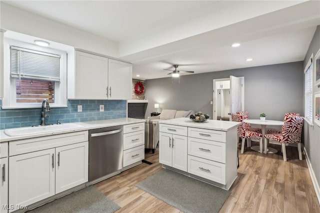 kitchen with dishwasher, sink, tasteful backsplash, light hardwood / wood-style floors, and white cabinets