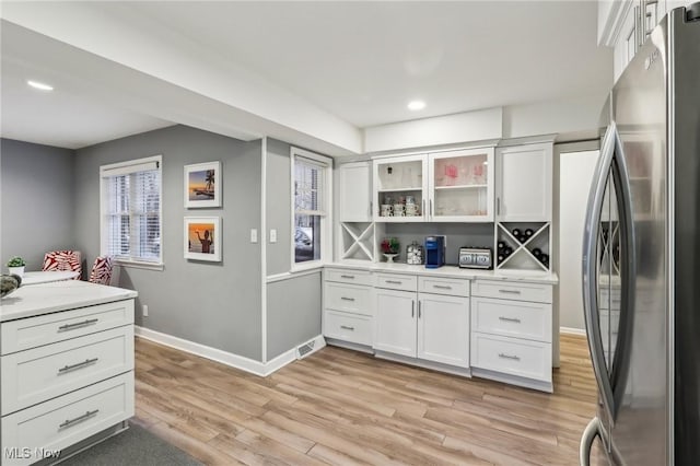 kitchen with white cabinetry, stainless steel fridge, and light hardwood / wood-style flooring