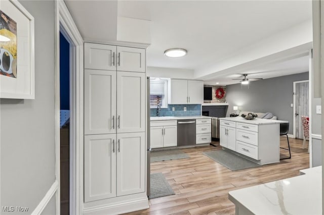 kitchen with white cabinetry, sink, ceiling fan, stainless steel dishwasher, and backsplash