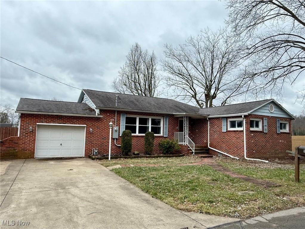 ranch-style home with a garage and a front lawn