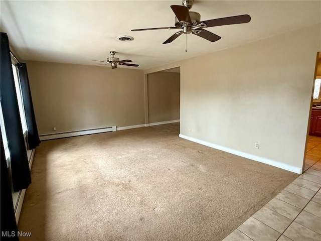 tiled spare room with ceiling fan and a baseboard heating unit