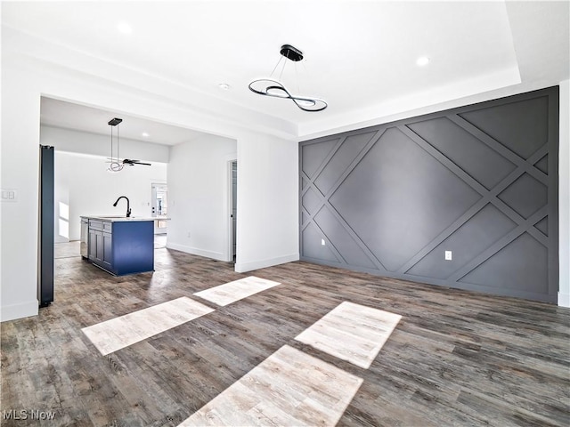 unfurnished living room featuring dark hardwood / wood-style floors, ceiling fan, and sink