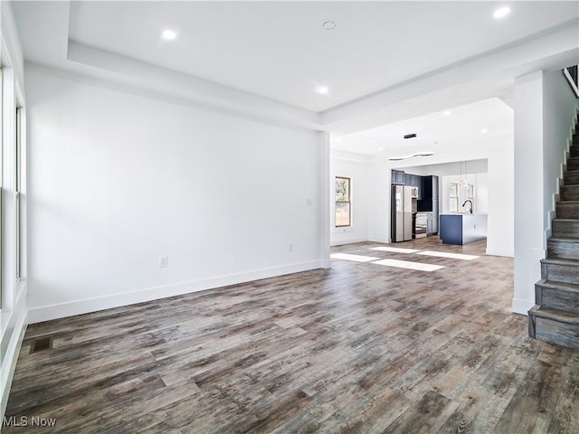 unfurnished living room featuring hardwood / wood-style flooring, a raised ceiling, and sink