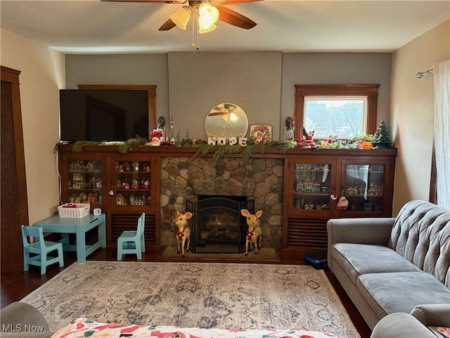 living room with hardwood / wood-style floors, ceiling fan, and a fireplace