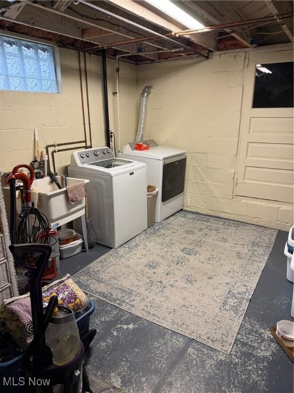 clothes washing area featuring separate washer and dryer and sink