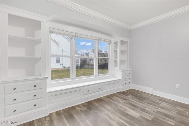 spare room featuring built in shelves, ornamental molding, and light hardwood / wood-style flooring