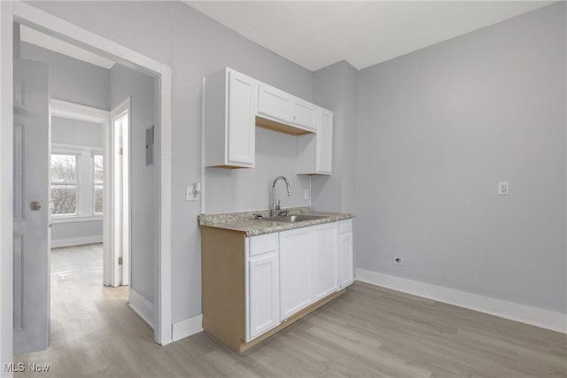 kitchen with white cabinets, light hardwood / wood-style floors, and sink