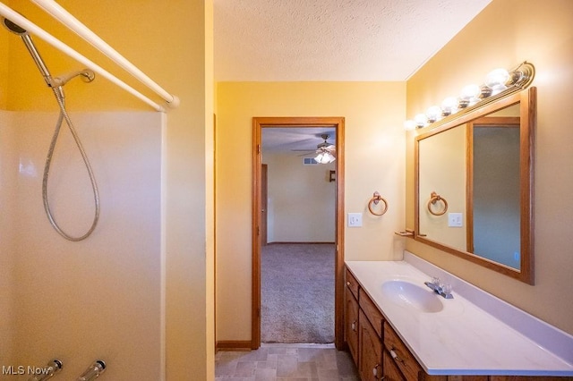 bathroom with walk in shower, a textured ceiling, vanity, and ceiling fan