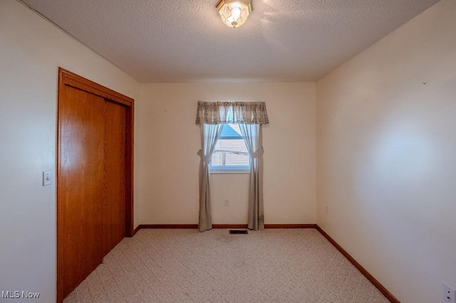 unfurnished bedroom with light carpet, a textured ceiling, and a closet