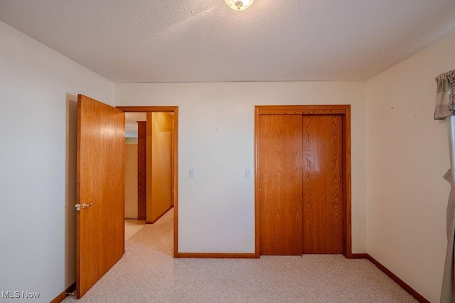 unfurnished bedroom with light carpet, a closet, and a textured ceiling
