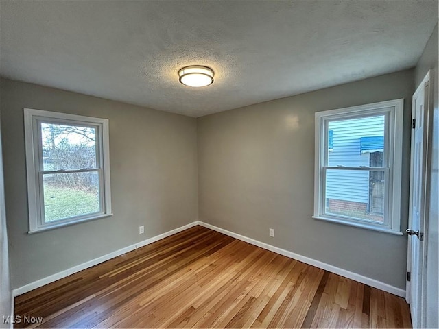 spare room featuring hardwood / wood-style flooring, a healthy amount of sunlight, and a textured ceiling