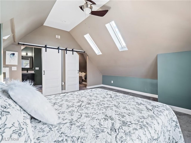 bedroom with vaulted ceiling with skylight, connected bathroom, ceiling fan, a barn door, and carpet floors