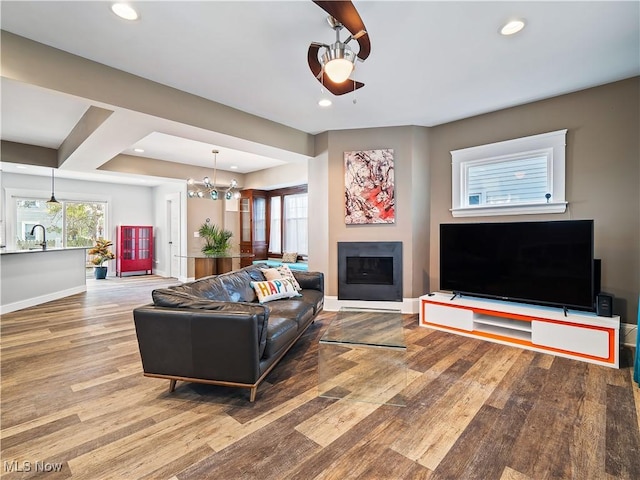 living room featuring ceiling fan with notable chandelier, hardwood / wood-style flooring, and sink