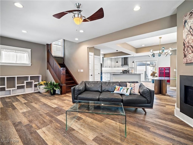 living room featuring a fireplace, hardwood / wood-style floors, and ceiling fan with notable chandelier