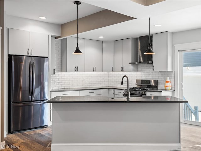 kitchen featuring appliances with stainless steel finishes, dark hardwood / wood-style flooring, tasteful backsplash, wall chimney exhaust hood, and pendant lighting