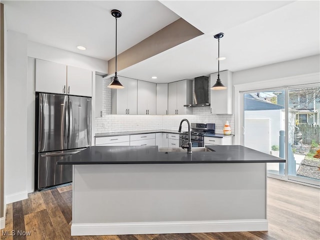 kitchen with pendant lighting, hardwood / wood-style floors, wall chimney exhaust hood, decorative backsplash, and appliances with stainless steel finishes